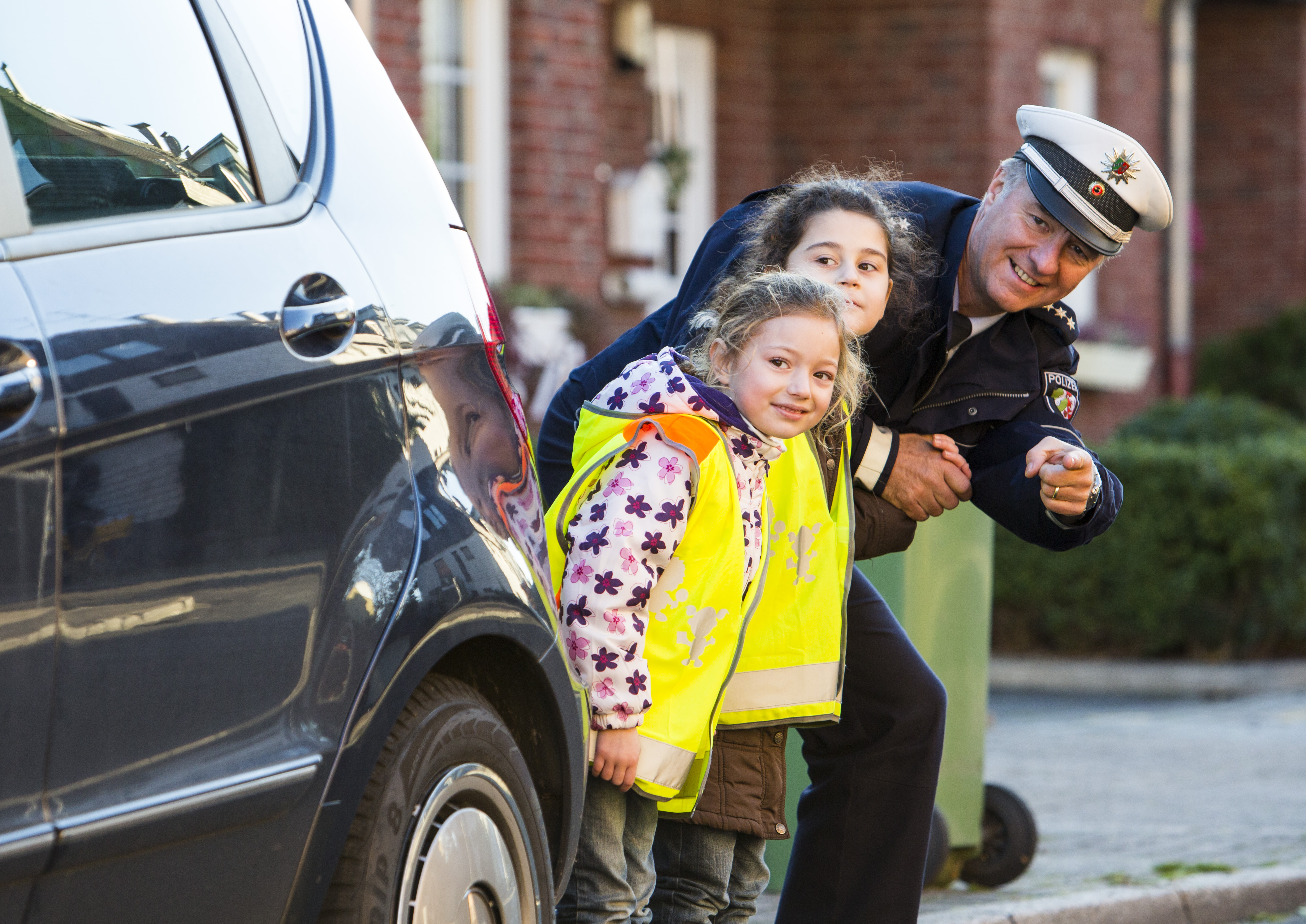 Ein Polizeibeamter übt mit Kindern das sichere Verhalten im Straßenverkehr